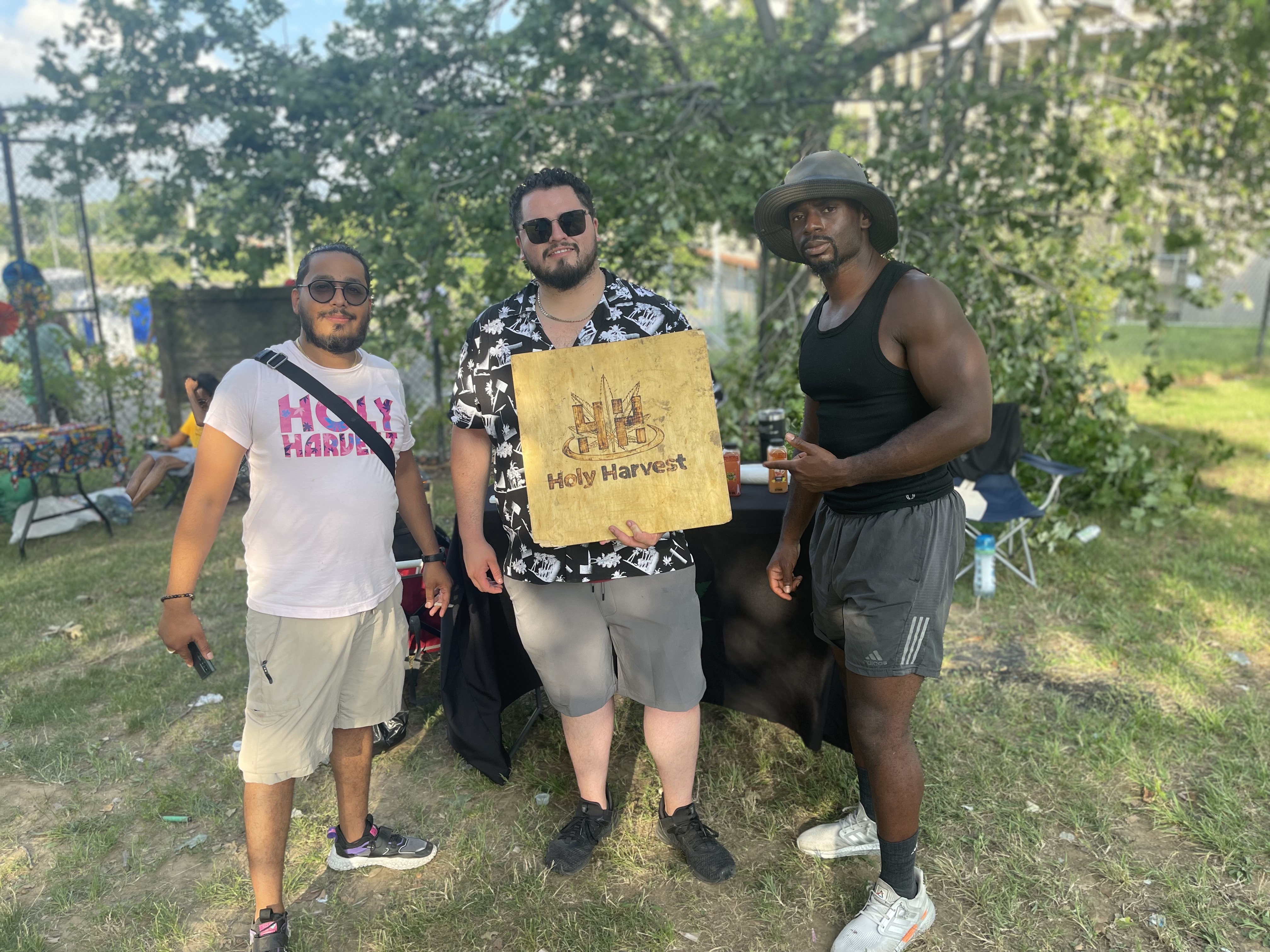 Founder with two guests holding a Holy Harvest sign